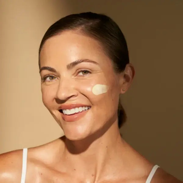 Woman applying Alastin A-LUMINATE Brightening Serum on her face for a glowing complexion.