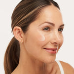A woman applying Alastin C-RADICAL Defense Antioxidant Serum on her face for brightening and firmness.