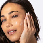 Woman applying Alastin HA IMMERSE Serum to her face to enhance hydration and smooth skin texture.