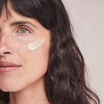 Close-up of a woman's face applying Alastin Renewal Retinol 0.25 on her cheek for skin renewal.