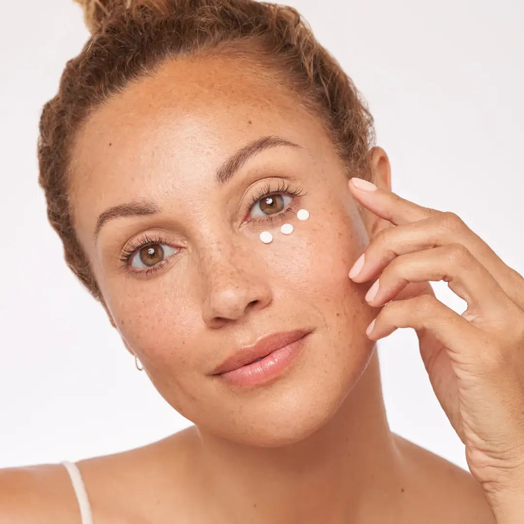 Woman applying Alastin Restorative Eye Complex treatment under her eyes for brightening and firming.