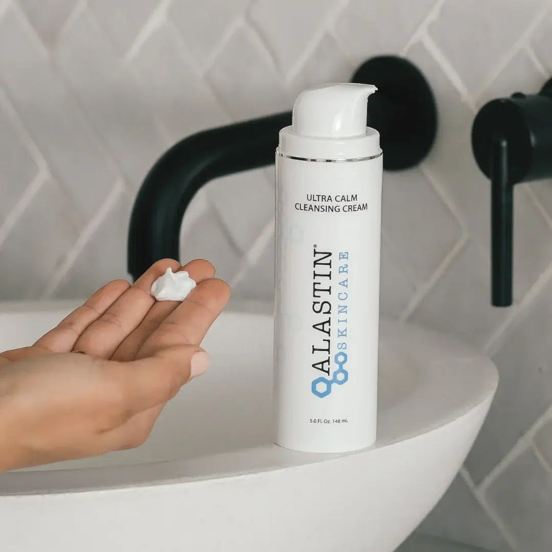 Alastin Ultra Calm Cleansing Cream in a hand above a sink, showcasing its soothing properties for skin.