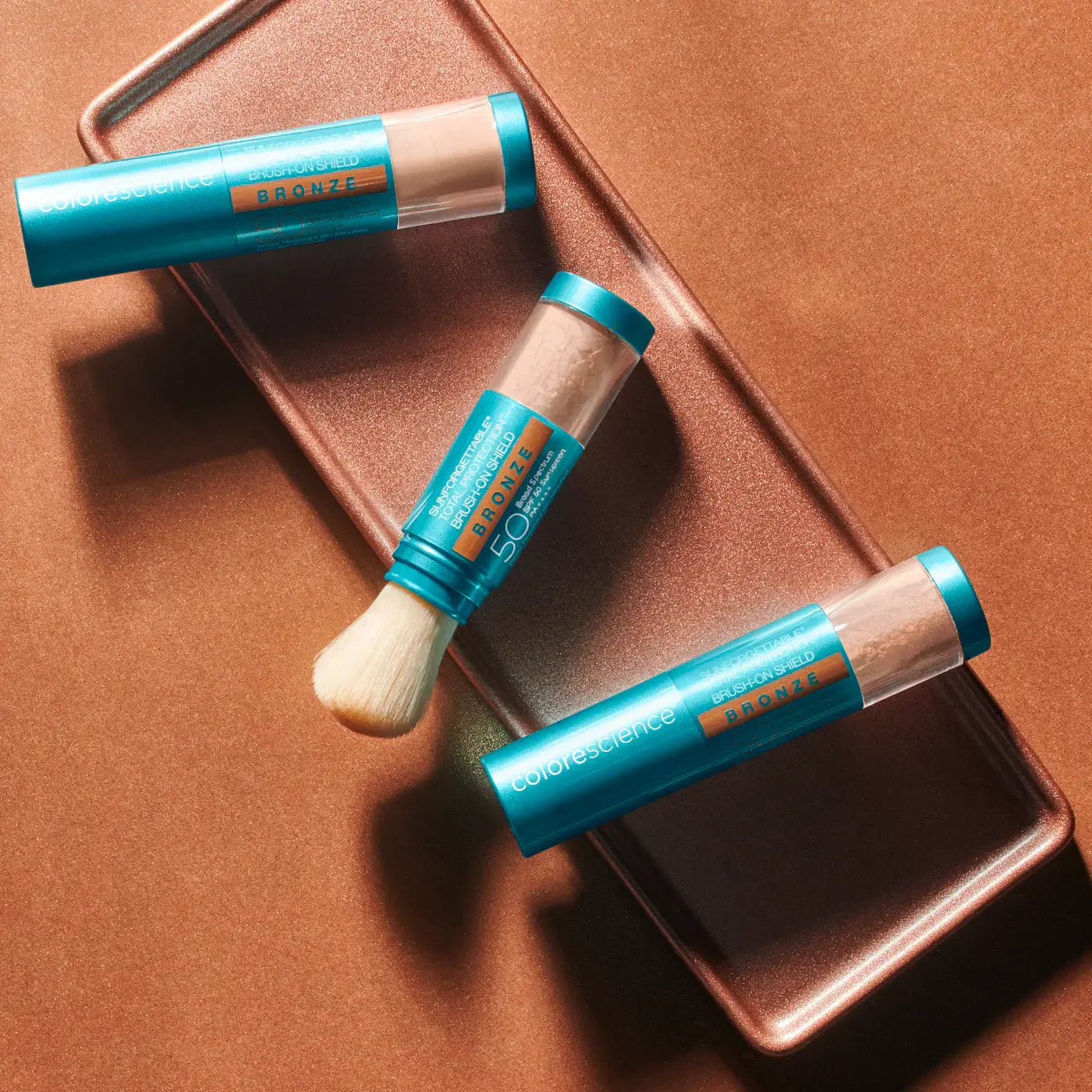 Colorescience Sunforgettable Total Protection Brush-On Shield Bronze SPF 50 product packaging on a bronze background.